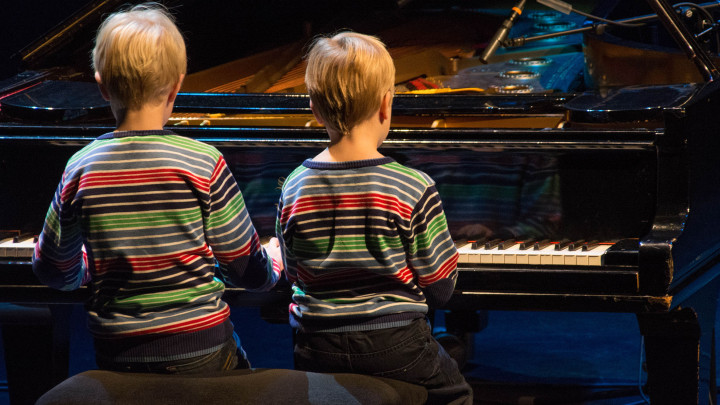 Pojat soittavat pianoa
